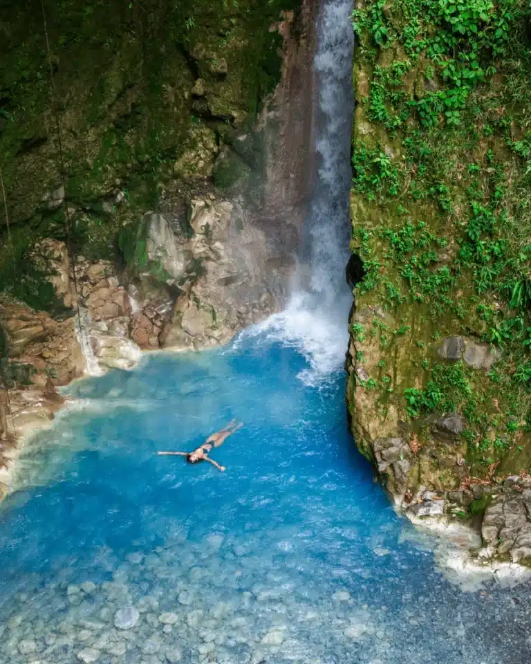 Swimmer floating in a turquoise waterfall pool at Sensoria